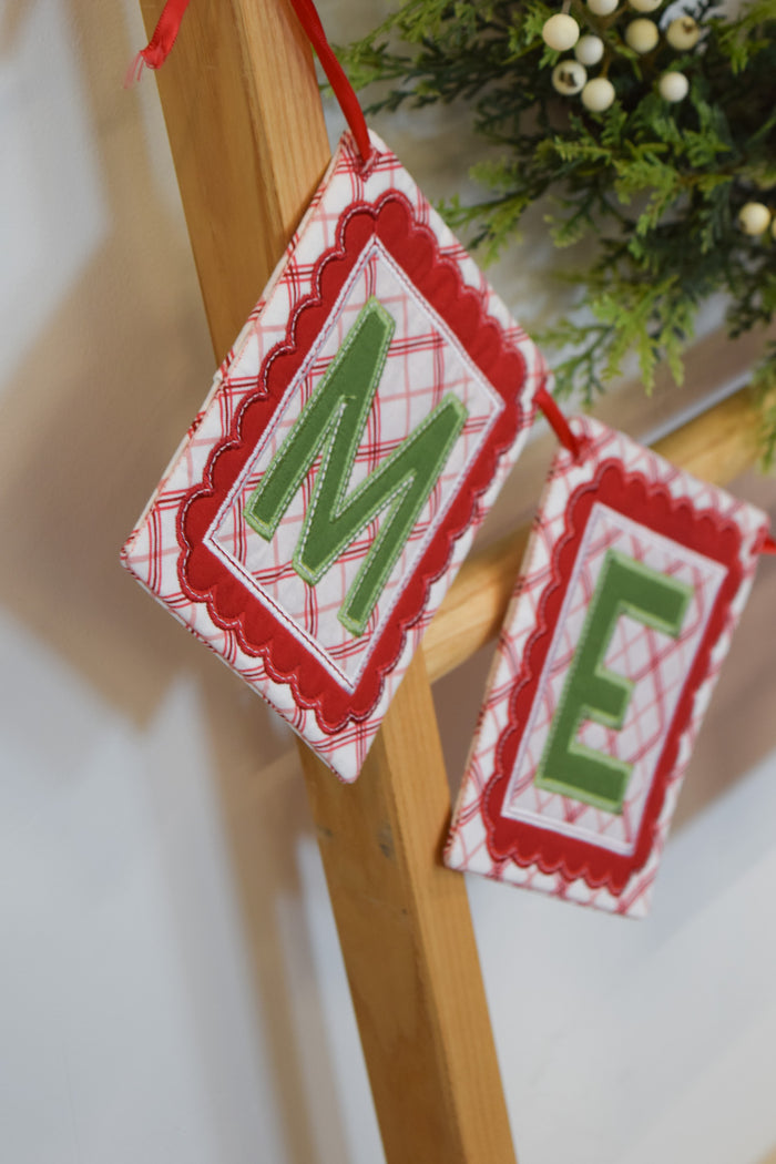 Decorative Christmas banner with 'M E' letters on a wooden stand.